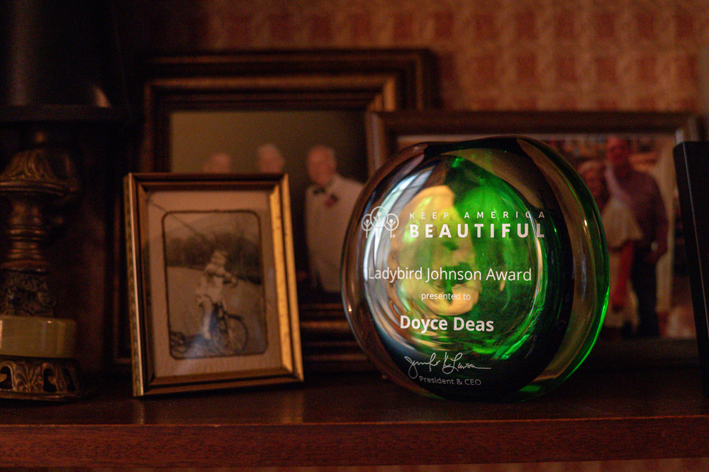 On a shelf, a glass paperweight listing, “Keep America Beautiful Ladybird Johnson Award Presented to Doyce Deas.”
