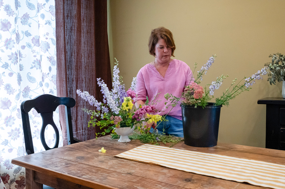A person arranges colorful flowers.