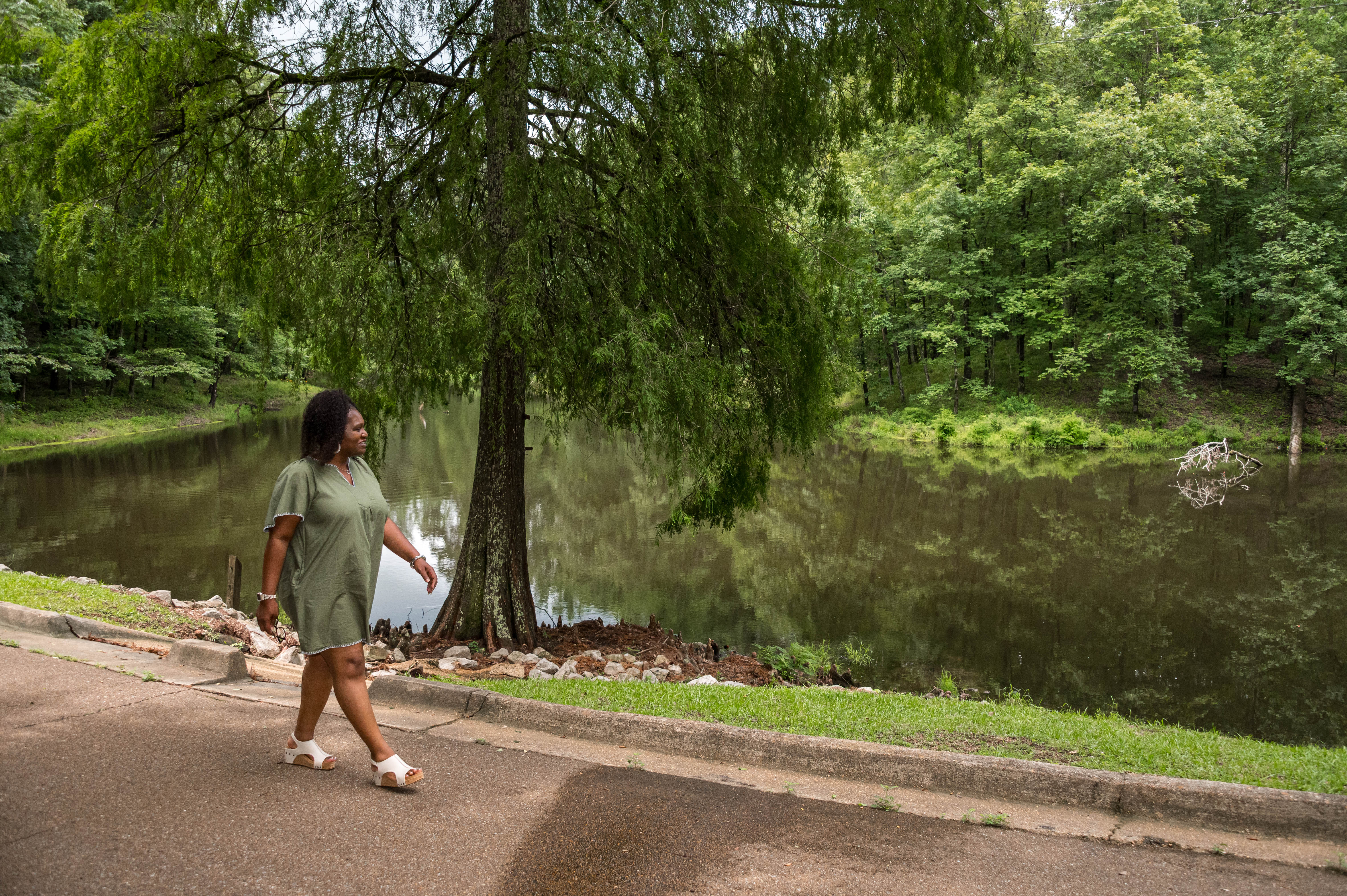 A person walking beside a pond.