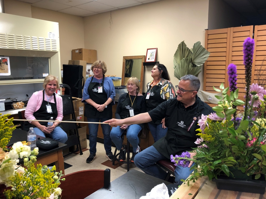 Floral design students listening to teacher provide a critique.