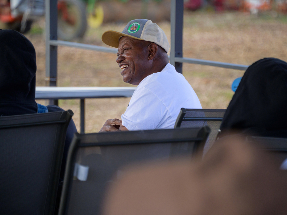 A seated man wearing a baseball hat and smiling.