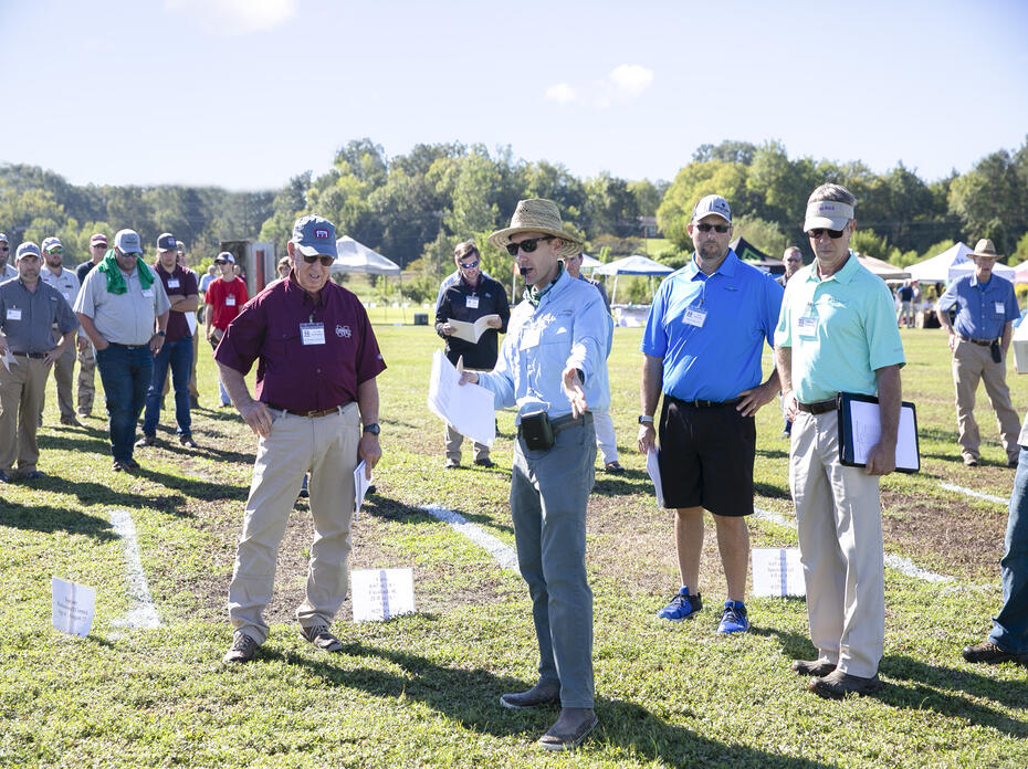 A group of people stand in a grassy field.