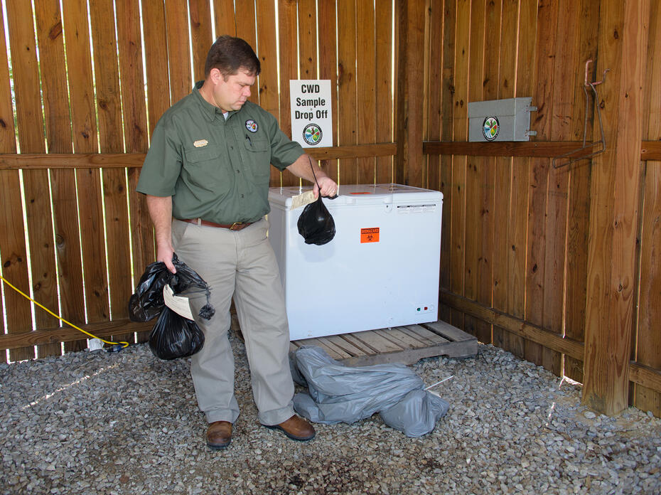 A man holds items in an open shed.