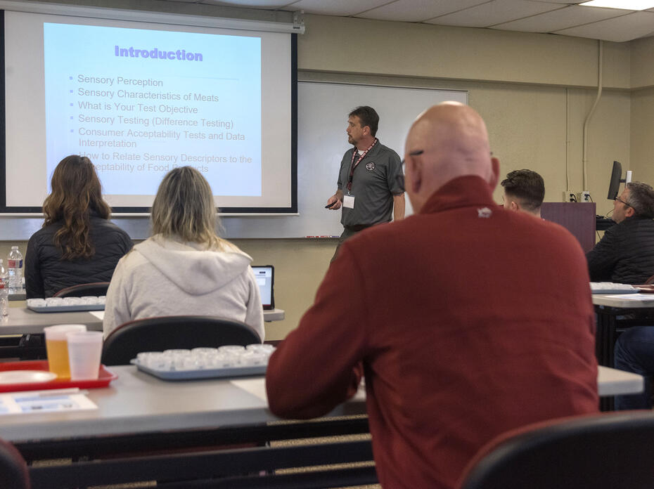 A man lectures from the front of a classroom.