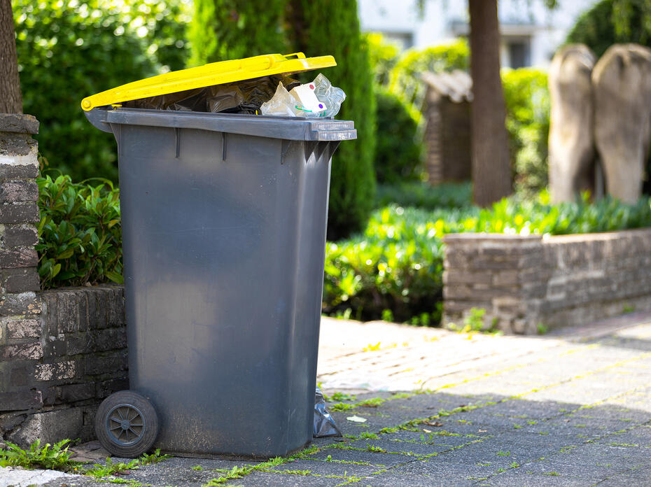 Full trash can sitting at the curb awaiting collection