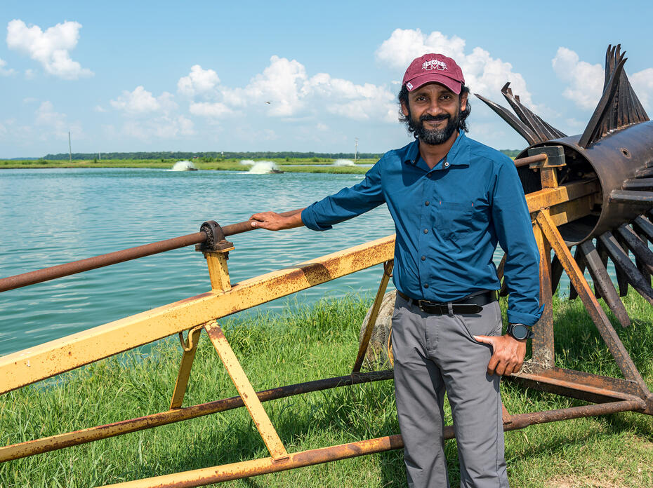 A man stands outdoors by a piece of farm machinery.