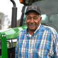 A smiling man standing in front of a green tractor.