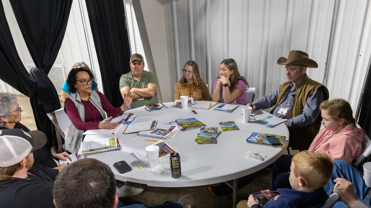 A circle of people sit in a meeting around a table.