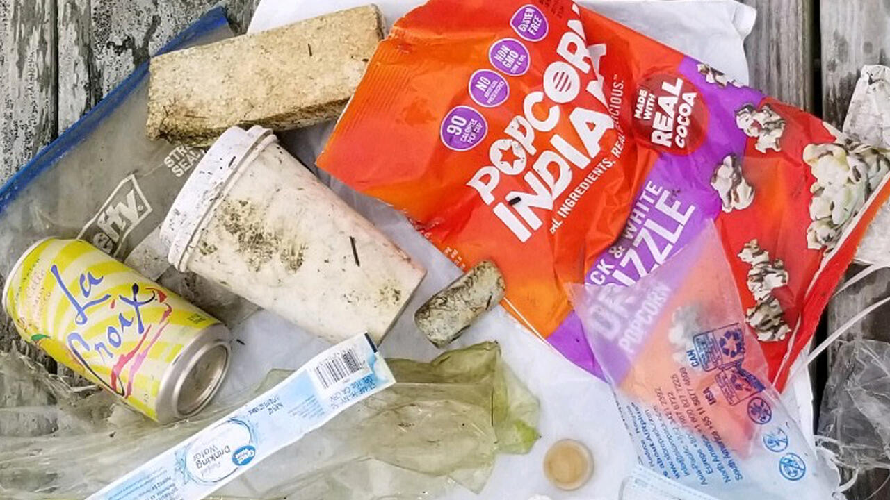 An assortment of litter retrieved from a watershed displayed on a wooden dock. 
