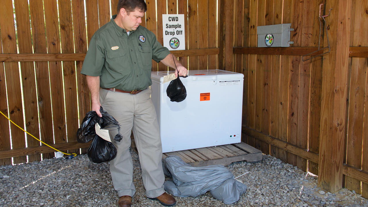 A man holds items in an open shed.
