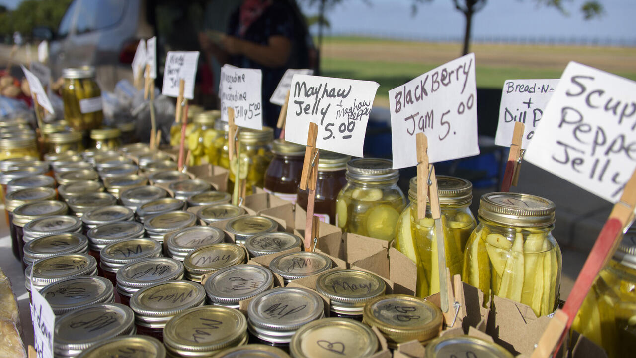 Glass jars filled with produce are lined up with price tags.