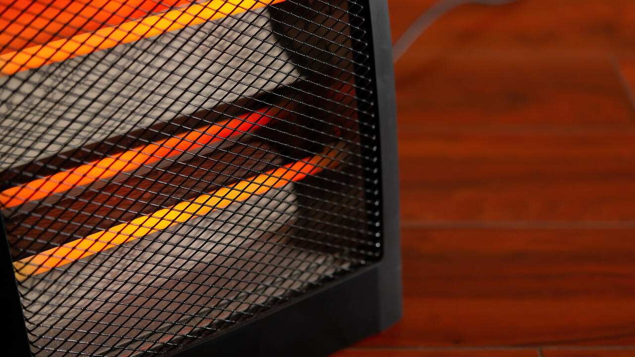 Close up of an electric space heater sitting on a hardwood floor.