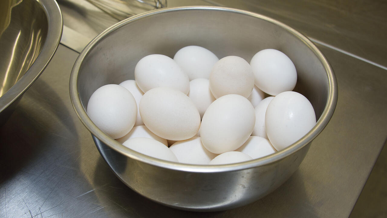 White eggs fill a metal bowl on a countertop.