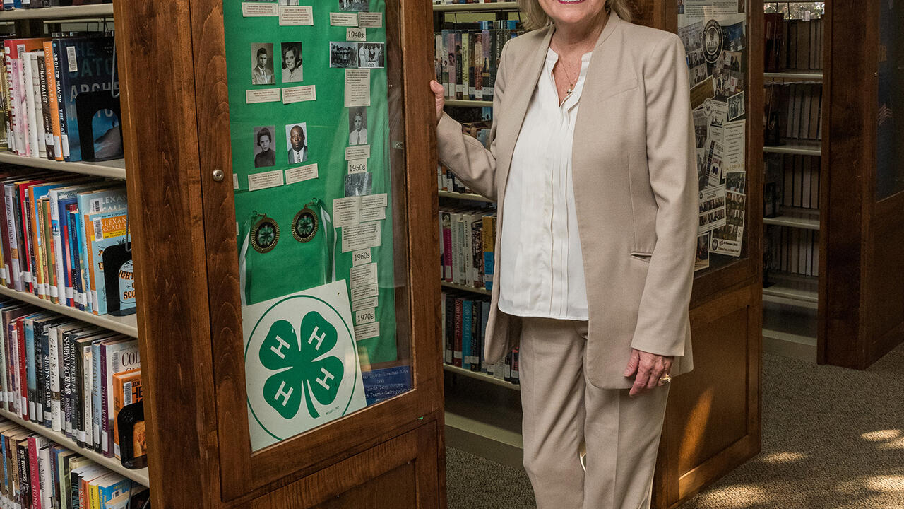 U.S. Senator Cindy Hyde-Smith stands next to a display case in a library.