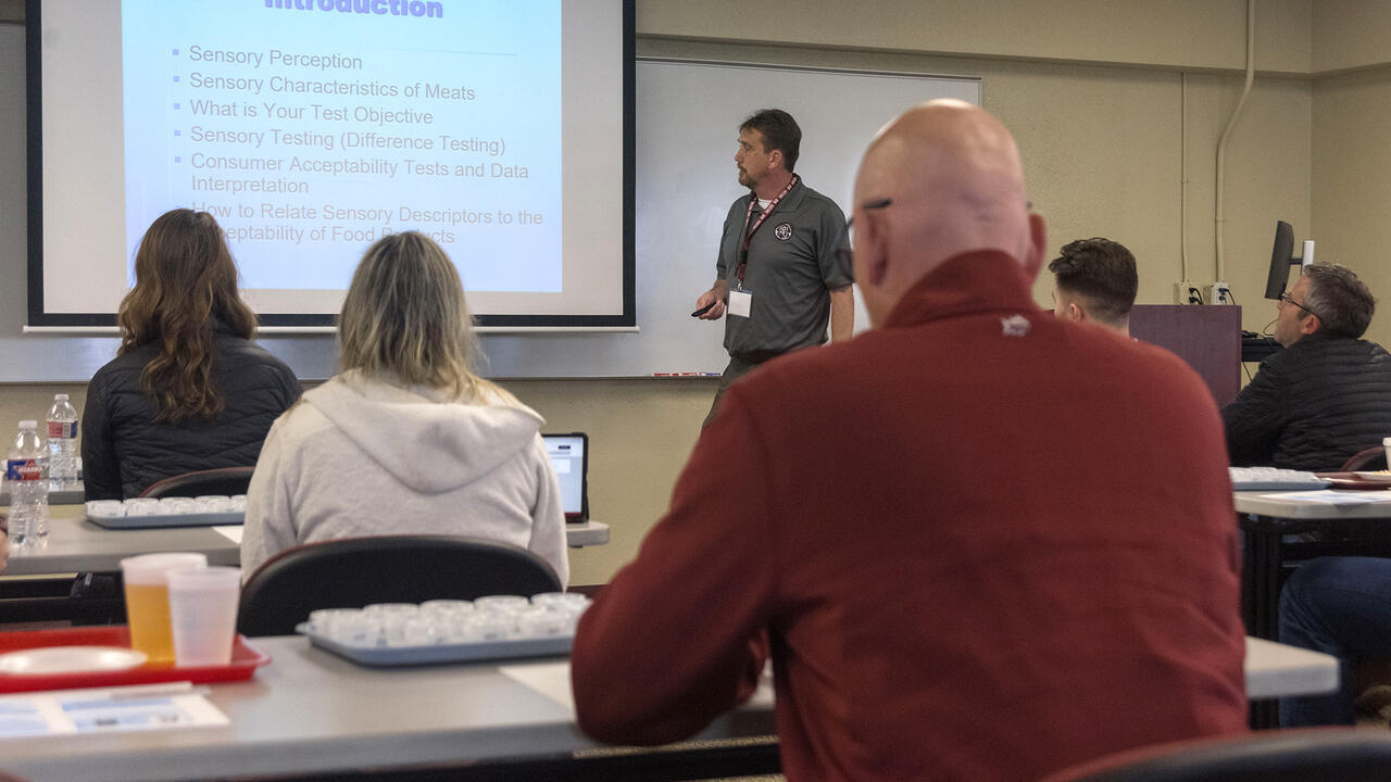 A man lectures from the front of a classroom.
