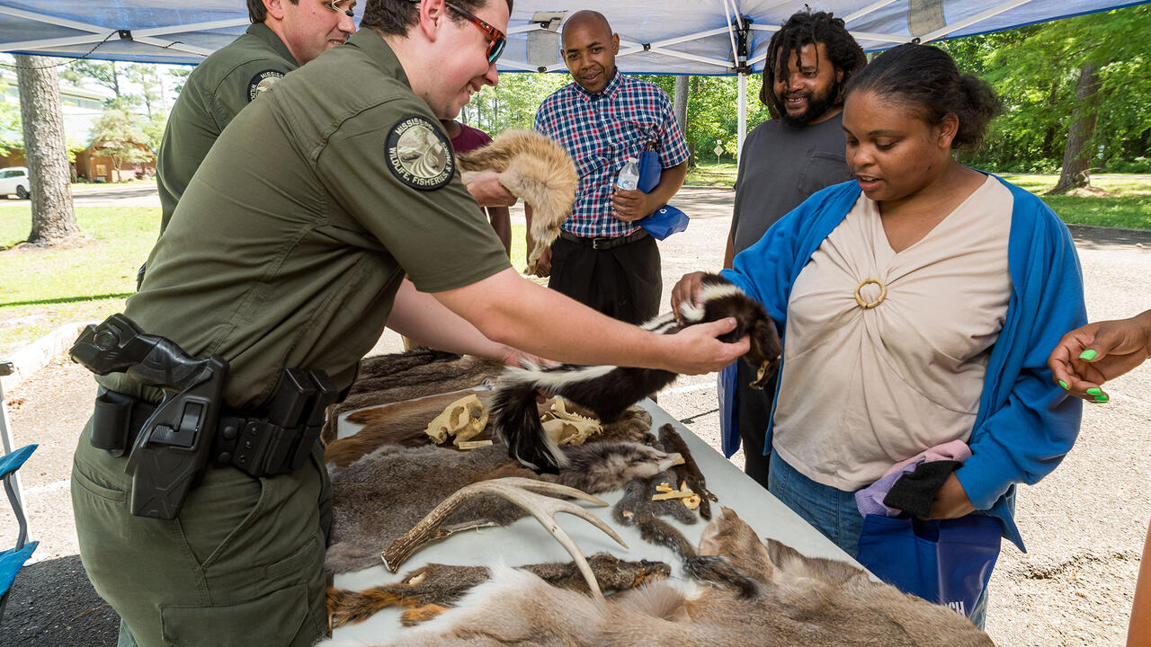 A man holds out a fur skin for a woman to touch.