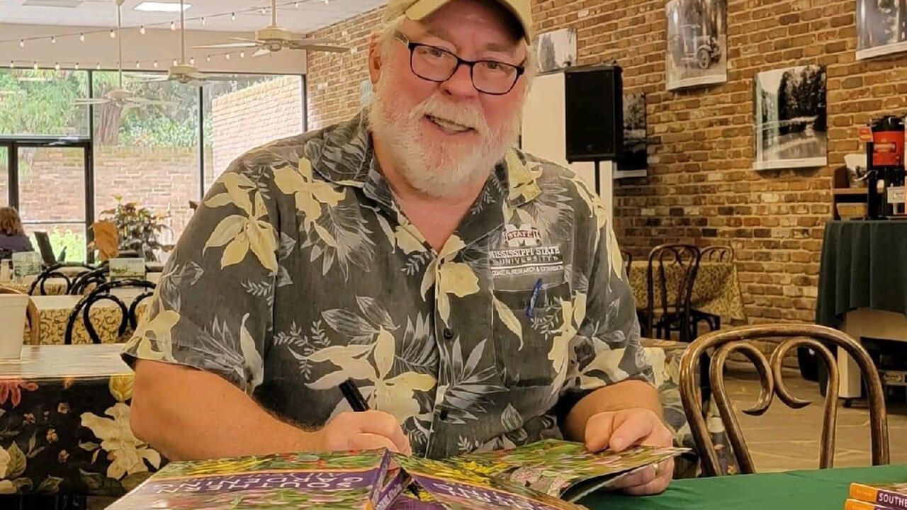 A man sits at a table with books.