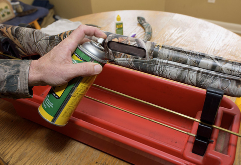 A person uses an aerosol can to remove particles and dust around ammunition chamber.