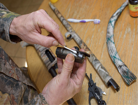 A cotton swab is used to clean a gun part.