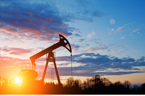 Oil drilling rig silhouetted against a sunset sky.