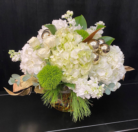 Arrangement of white flowers, gold ornaments, gold leaves, and green foliage.