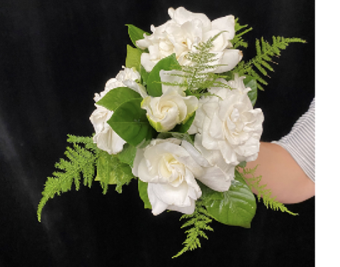 Gardenia flowers, shiny leaves, and fern-like foliage gathered into a bouquet.