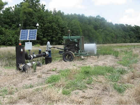 A large pump system in a field, with a piece of equipment attached to it. 