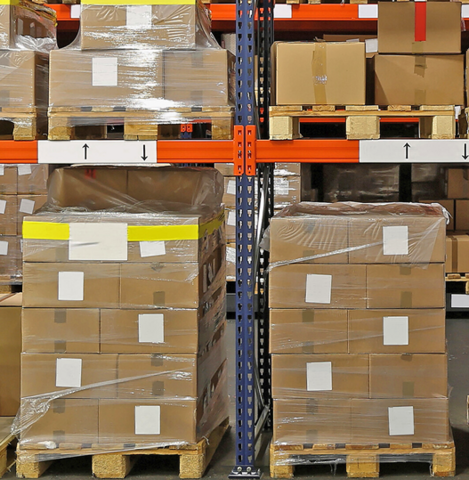 Stacks of cardboard boxes on wood pallets. Each pallet's boxes are shrinkwrapped together, and each box has a label. 
