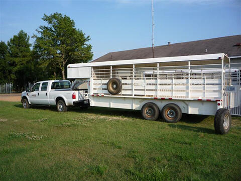 A white trailer hitched to a white pickup truck.