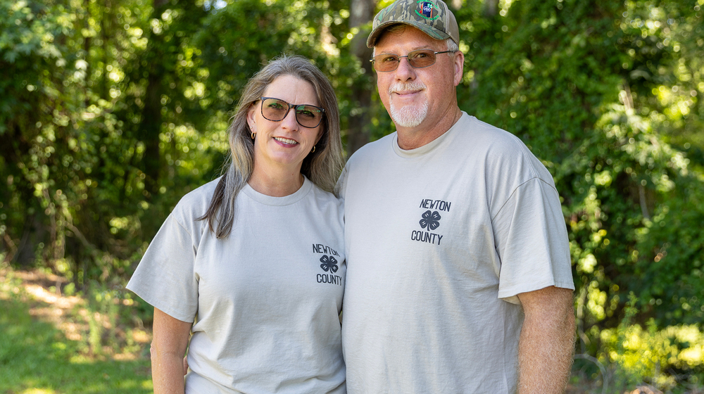 Two people wearing Newton County 4-H shirts standing outside and smiling.