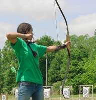 A girl in a green shirt draws back on a bow